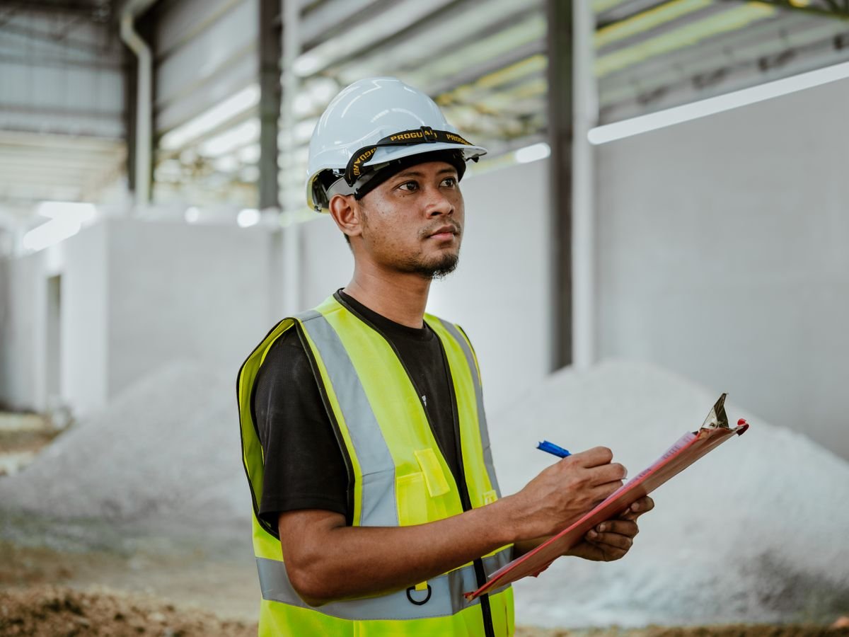 Auditor with a clipboard inspecting a factory floor